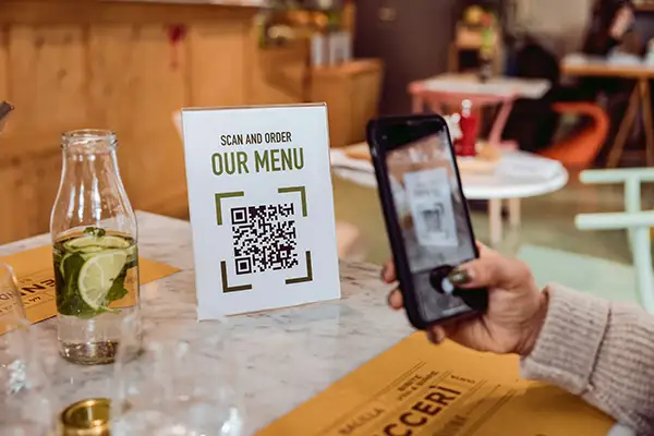 Branding & Kommunikation: QR-Code auf einem Tischaufsteller mit der Aufschrift ‚Scan and Order – Our Menu‘ in einem Café