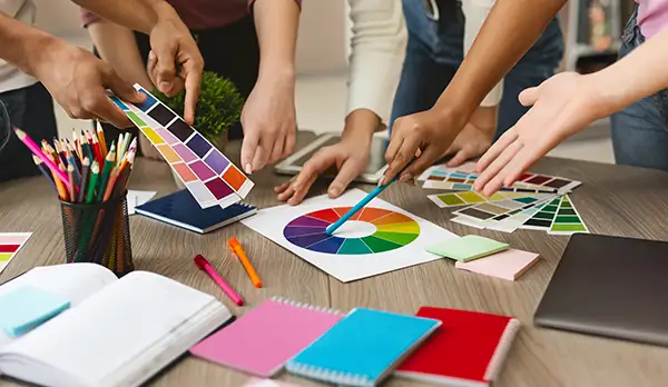 Team arbeitet mit Farbfächern und Farbkreis an einem Corporate Design Konzept