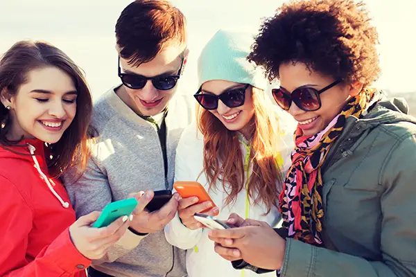 Social Media Management - Drei junge Erwachsene schauen lachend auf ihre Smartphones – Symbol für erfolgreiche Social-Media-Betreuung
