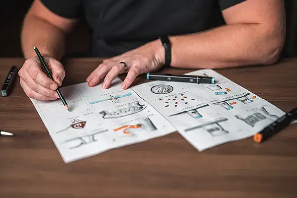 Person zeichnet Skizzen und Layouts für Printdesign auf Papier