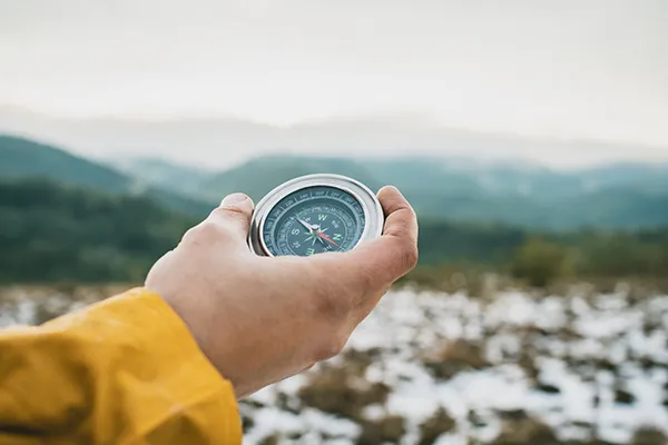 Person hält Kompass für Richtungssuche - Thema: Kostenloser Digitalcheck